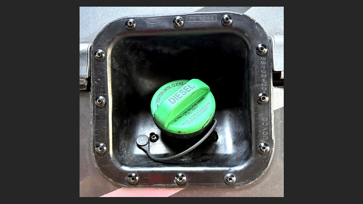 Before: Exposed green diesel fuel cap on motorhome chassis — unprotected, vulnerable to fuel theft, siphoning, and contamination